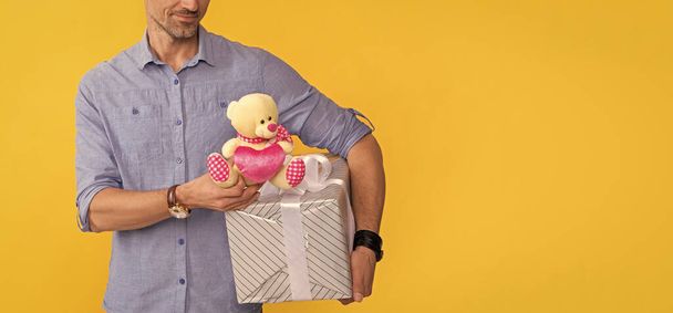 обрезанный зрелый мужчина держать коробку и игрушку на желтом фоне, копировать пространство, юбилей . - Фото, изображение