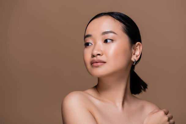 Young asian woman with naked shoulders looking away isolated on brown  - Foto, Imagen