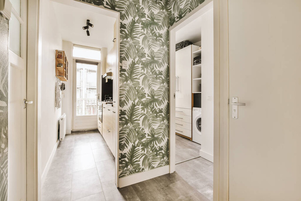 egy szoba tapétázott mintával a falakon, és egy nyitott ajtó, ami egy mosógéphez vezet. - Fotó, kép
