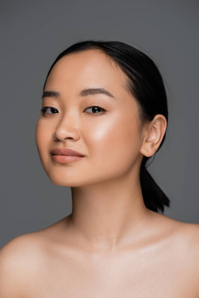 Young asian woman with naked shoulders looking at camera isolated on grey  - Foto, Imagen