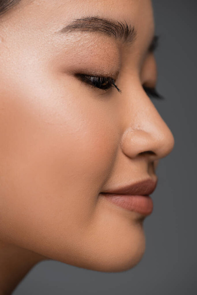 Close up view of young asian woman with makeup posing isolated on grey  - Photo, Image
