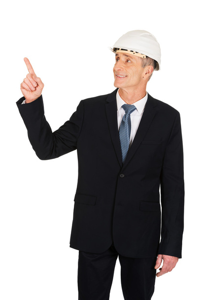 Mature engineer with hard hat pointing up - Photo, image