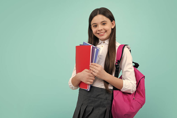 Schoolchild, teenage student girl with school bag backpack hold book on blue isolated studio background. Children school and education concept - Foto, Imagen