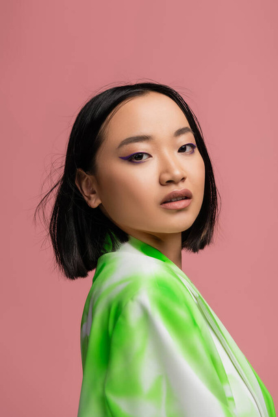 portrait of young asian woman with makeup looking at camera isolated on pink - Foto, Imagem