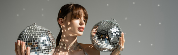 young woman holding shiny and vintage disco balls on grey background, banner  - Fotoğraf, Görsel
