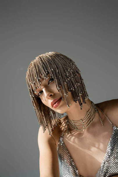 model with metallic headwear with jewelry looking at camera isolated on grey  - Zdjęcie, obraz