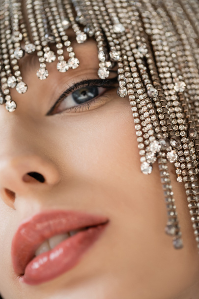 Cropped view of young woman in headwear with rhinestones looking at camera on grey background  - Fotó, kép