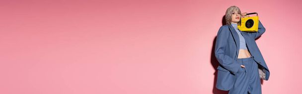 Модна жінка в ювелірній головній убірці, що тримає бумбокс на рожевому фоні з тіні, банер
  - Фото, зображення