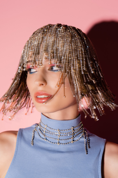 Motion blur of stylish woman in jewelry headwear looking away on pink background  - Fotó, kép