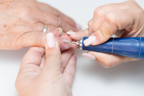 Close-up de uma verdadeira manicure feminina raspando uma cutícula de unhas de mulheres seniores com um buffer de unhas - Foto, Imagem