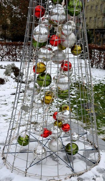 輝くボールでいっぱいのクリスマスツリーの形をした円錐形のワイヤー構造。グリッドはLEDで覆われています. - 写真・画像