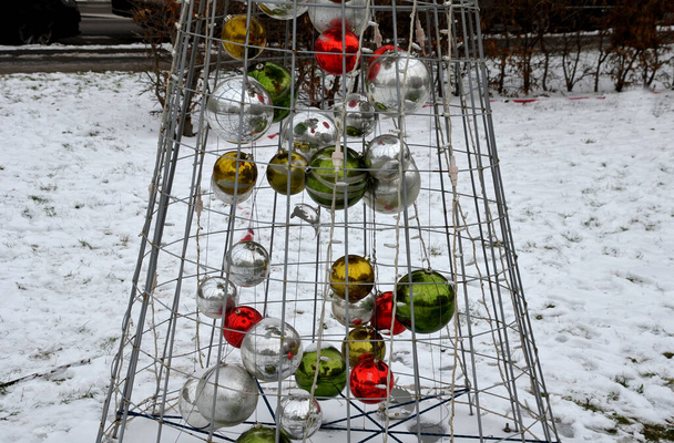 Kegelförmige Drahtstruktur in Form eines Weihnachtsbaums, gefüllt mit glitzernden Kugeln. das Gitter ist mit LED-Lampen bedeckt. - Foto, Bild