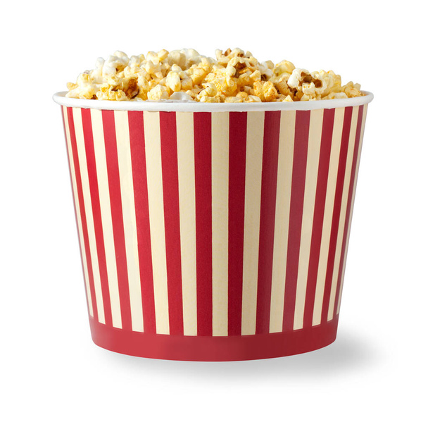 Paper striped bucket with popcorn isolated on white background with clipping path. Concept of cinema or watching TV. - Photo, Image