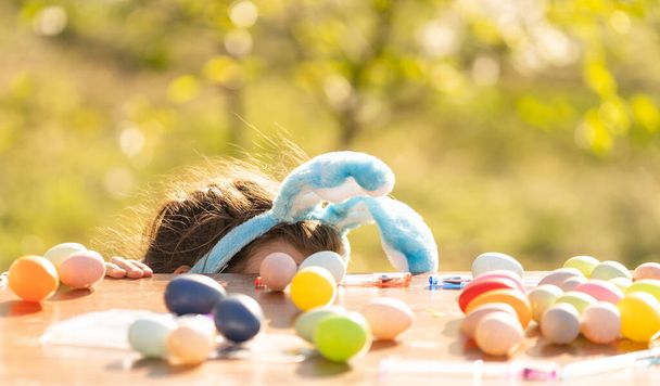 mignonne adolescente portant des oreilles de lapin et tenant des œufs de Pâques contre le jardin. - Photo, image