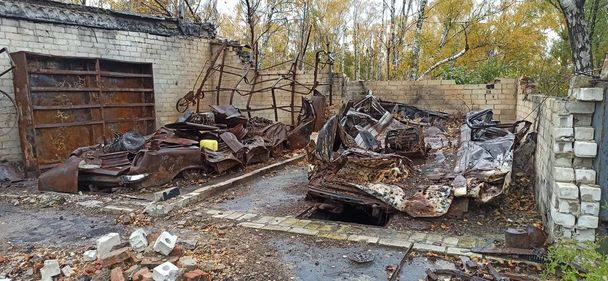 Spálená auta v zničených garážích během války na Ukrajině. Zničená auta. Spálená doprava po ostřelování ruské armády města na Ukrajině. Rusko-ukrajinská válka. Zničené budovy a auta během války - Fotografie, Obrázek