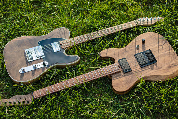 E-Gitarren liegen auf grünem, frischem Gras im Sonnenlicht - Foto, Bild