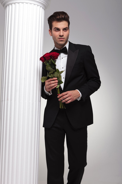  ο άνθρωπος των επιχειρήσεων κρατώντας την ανθοδέσμη των κόκκινων τριαντάφυλλων στο χέρι - Φωτογραφία, εικόνα
