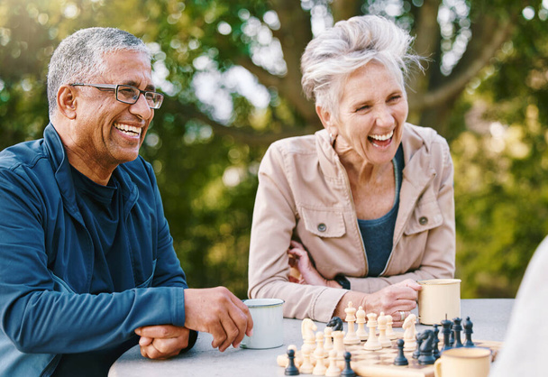Happy, chess or couple of friends in nature playing a board game, bonding or talking about a funny story. Park, support or healthy senior people laughing at a joke and enjoying quality relaxing time. - Фото, изображение