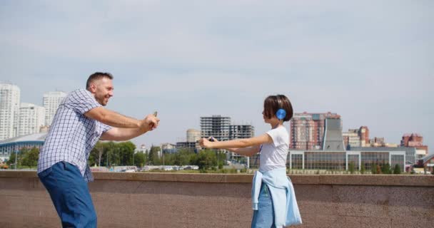 Oslavujeme začátek letních prázdnin - otec a dcera tančí na pozadí městského prostředí. Samotný rodičovský koncept. Zpomalený záznam 4k. - Záběry, video