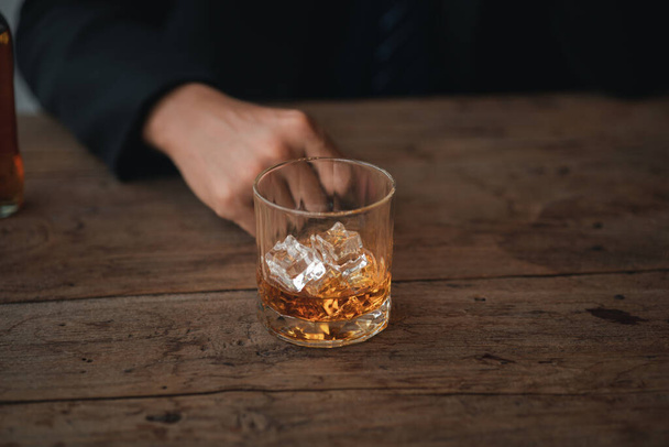 Een man met een glas cognac drinkt brandewijn in een bar, drinkt alcohol en kan de rijvaardigheid aantasten en de gezondheid schaden. Het begrip alcohol drinken. - Foto, afbeelding