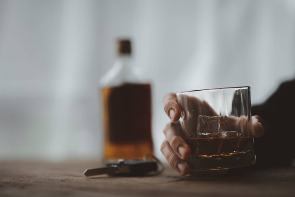 Hombre sosteniendo una copa de brandy, que está bebiendo brandy en un bar, beber alcohol perjudica la capacidad de conducción y puede dañar la salud. El concepto de beber alcohol. - Foto, imagen