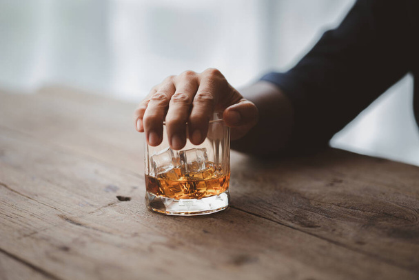 Een man met een glas cognac drinkt brandewijn in een bar, drinkt alcohol en kan de rijvaardigheid aantasten en de gezondheid schaden. Het begrip alcohol drinken. - Foto, afbeelding