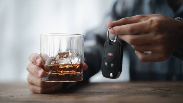 Hombre sosteniendo una copa de brandy, que está bebiendo brandy en un bar, beber alcohol perjudica la capacidad de conducción y puede dañar la salud. El concepto de beber alcohol. - Foto, Imagen