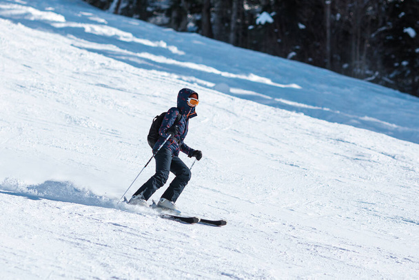 Amateur-Skifahrerin rutscht in Bergregion den Hang hinunter. - Foto, Bild