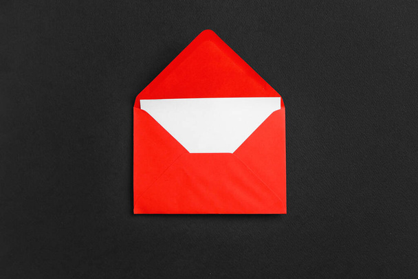 Красный бумажный конверт с карточкой на темном фоне - Фото, изображение