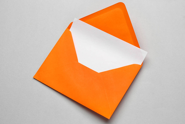Оранжевый бумажный конверт с карточкой на светлом фоне - Фото, изображение