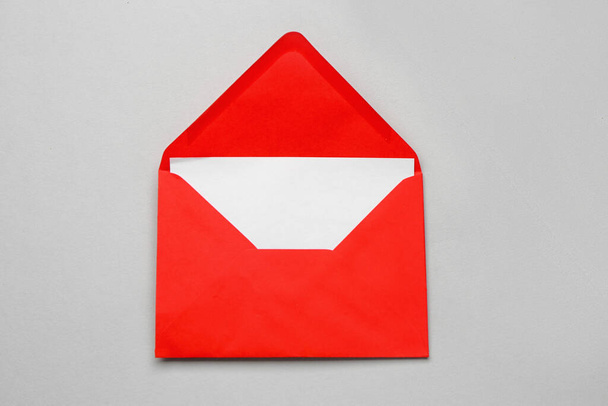 Sobre de papel rojo con tarjeta sobre fondo claro - Foto, imagen