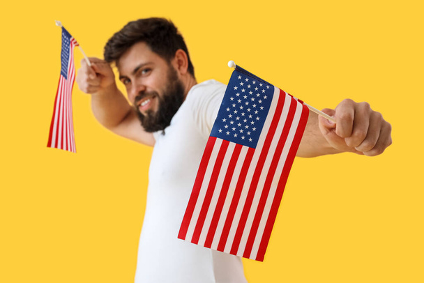 黄色の背景にアメリカの旗を持つハンサムな髭の男 - 写真・画像