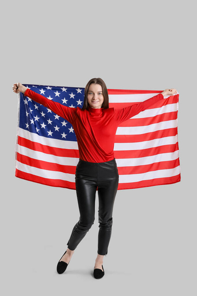 Nuori nainen, jolla on Yhdysvaltain lippu harmaalla pohjalla - Valokuva, kuva