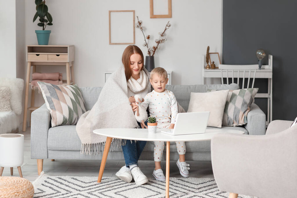Schöne Frau mit ihrem kleinen Sohn und Spielzeug sitzt auf grauem Sofa zu Hause - Foto, Bild