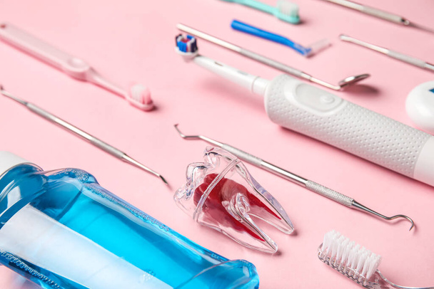 Dente di plastica con strumenti dentali e spazzole su sfondo rosa, primo piano - Foto, immagini