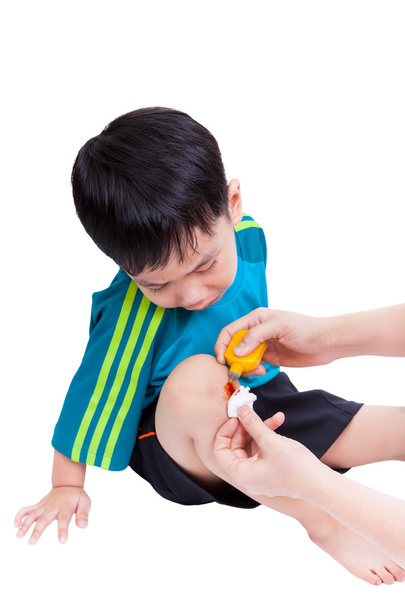 Маленький азіатський хлопчик дивиться рану ноги
 - Фото, зображення