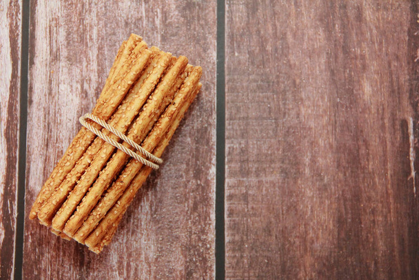 Palitos largos de pan de sésamo seco sobre un fondo marrón - Foto, imagen