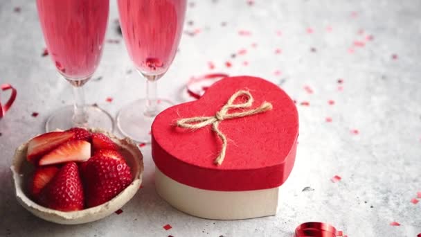 Bottle of rose champagne, two glasses with fresh ripe strawberries and heart shaped boxed gift, placed on stone table for a special romantic occasion or Valentines. With copy space - Footage, Video
