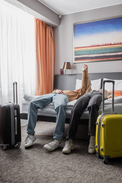 young couple of travelers holding hands and showing triumph gesture near suitcases in hotel bedroom - Foto, Imagem