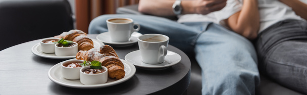 tasty croissants with jam and chocolate paste near coffee cups and cropped couple on blurred background, banner - Foto, imagen