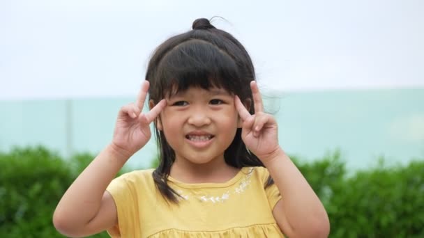 Retrato Divertido niña asiática gran niño sonriente mirando a la cámara y señalando sus mejillas, disfrutando del concepto testimonial de la infancia, Niño positivo, 4k metraje, Retrato de cámara lenta - Metraje, vídeo