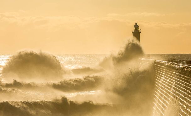 Grandes olas golpean el faro y el muelle norte protegiendo la boca del Tyne en Tynemouth al amanecer, Inglaterra - Foto, Imagen