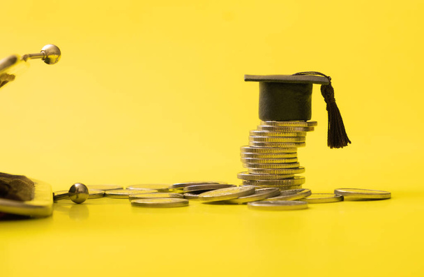 Graduated cap with coins and wallet fragment on yellow background. Savings for education concept. - Foto, Imagen