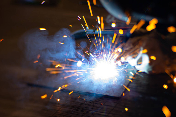 Soudeur de métaux travaille avec un soudeur d'acier dans une usine avec un équipement de protection. Fabrication de structures métalliques et services de réparation et de construction selon le concept de travail manuel. - Photo, image
