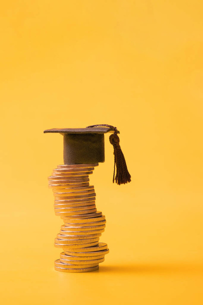 Graduated cap with coins on orange background. Savings for education concept. Copy space. - Foto, Imagen