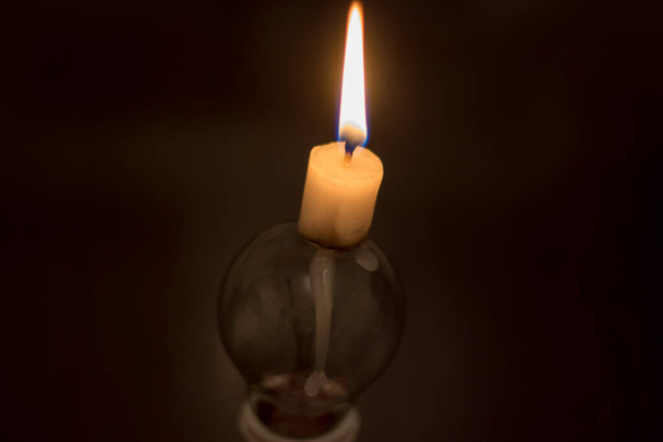 A burning candle and a broken lamp. Blackout due to war in Ukraine - Φωτογραφία, εικόνα