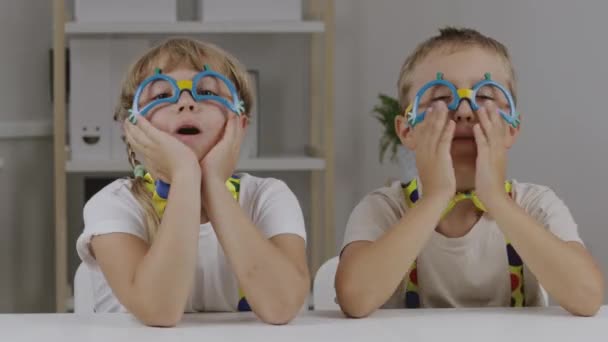Jongen en meisje zijn gekleed in clown jurk zijn nieuwsgierig naar iets. . Hoge kwaliteit 4k beeldmateriaal - Video