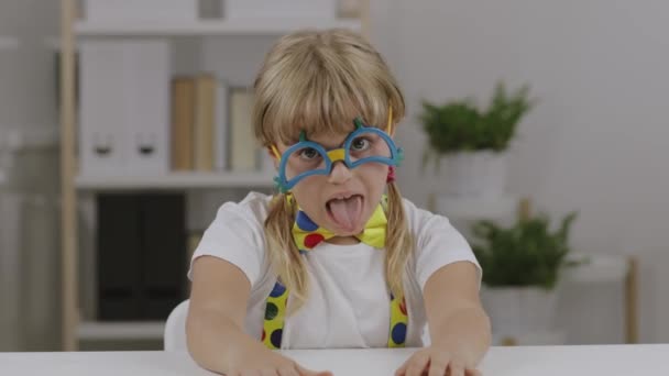 Zabawna dziewczyna od 7 lat ubrana w okulary klauna, motyla i szelki. Wysokiej jakości materiał 4k - Materiał filmowy, wideo
