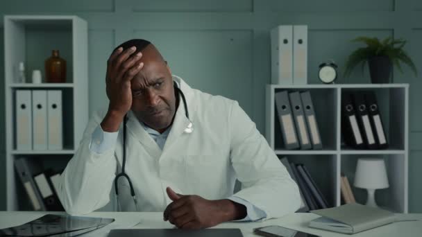 Pensive přemýšlivý smutný africký lékař etnický starší muž pocit zoufalství stres vyčerpaný unavený muž sedět v nemocnici myslet zdravotní problém deprese syndrom profesionální vyhoření smutný obličej emoce - Záběry, video