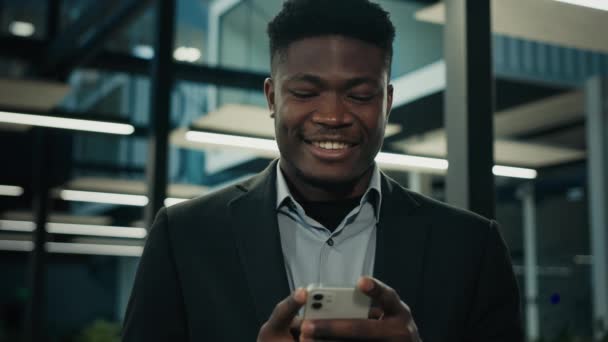 Африканський бізнесмен, молодий чоловік-підприємець, виконавчий працівник етнічний чоловік, який спілкується по телефону, посміхається, читає хороше мобільне повідомлення, спілкується в мережі бізнес-чат-комірки - Кадри, відео